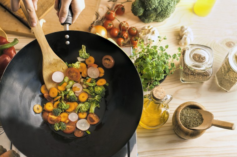 Chef cooking vegetables in wok pan