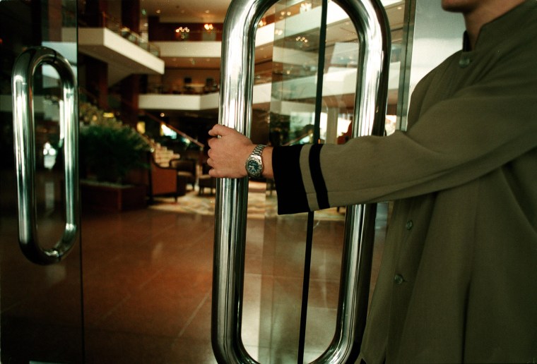 Image: A doorman opening the door to a luxury hotel foyer, 25 June 2002