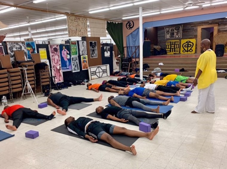 Sherri Doucette guides men in class in Savasana, a resting pose.