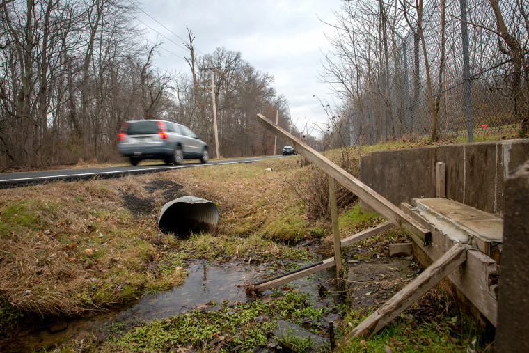 Water trickles through boards meant to stop runoff from the Willow Grove Naval Air Station Joint Reserve Base into a local creek in Horsham Township, Pa.