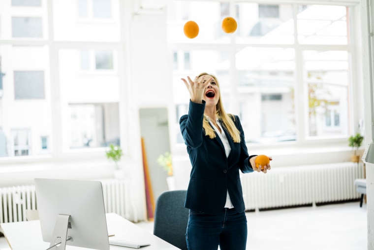 Carefree businesswoman juggling with oranges in office