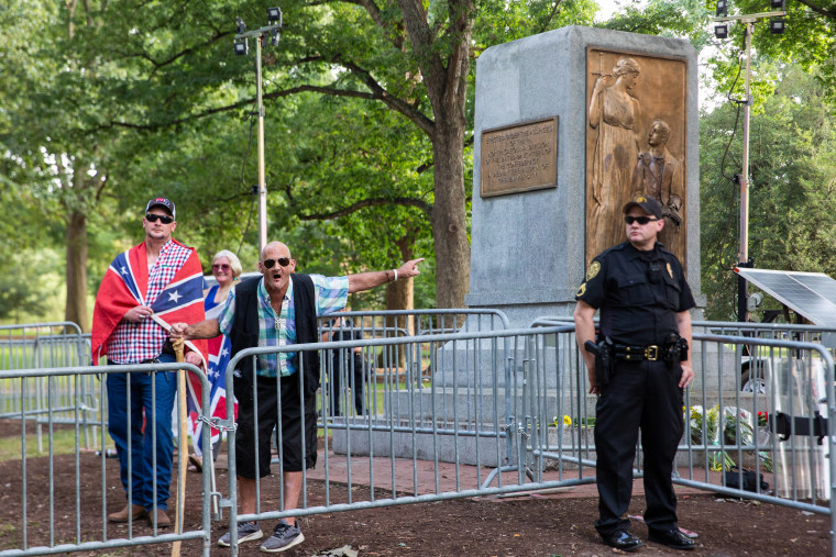 A Silent Sam supporter shouts at counter-demonstrators from behind a barricade, while pointing to the pedestal where the statue once stood.