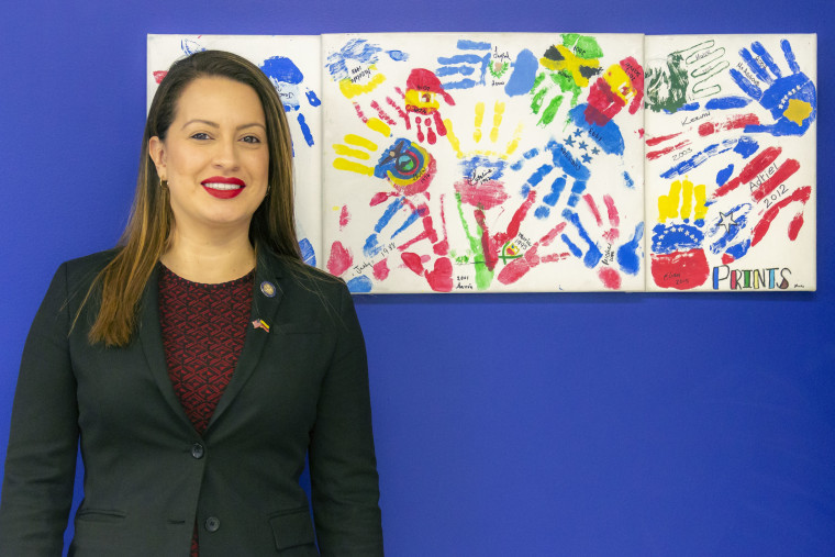 New York State Assemblywoman Catalina Cruz stands in her district office in Corona, Queens next to a painting picturing the handprints of middle school "Dreamers."