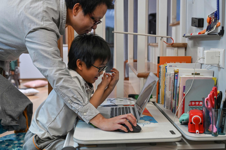 Image: Zhou Ziheng helping his son Vita to create a game with coding on his laptop at their home in Shanghai o