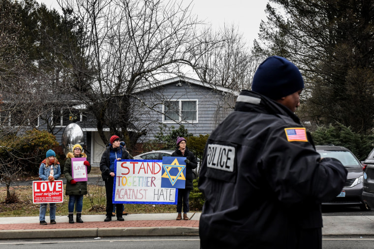 Image: People hold signs of support near the home of a rabbi where five people were stabbed in an attack during a Hannukah party in Monsey, N.Y., on Dec. 29, 2019.