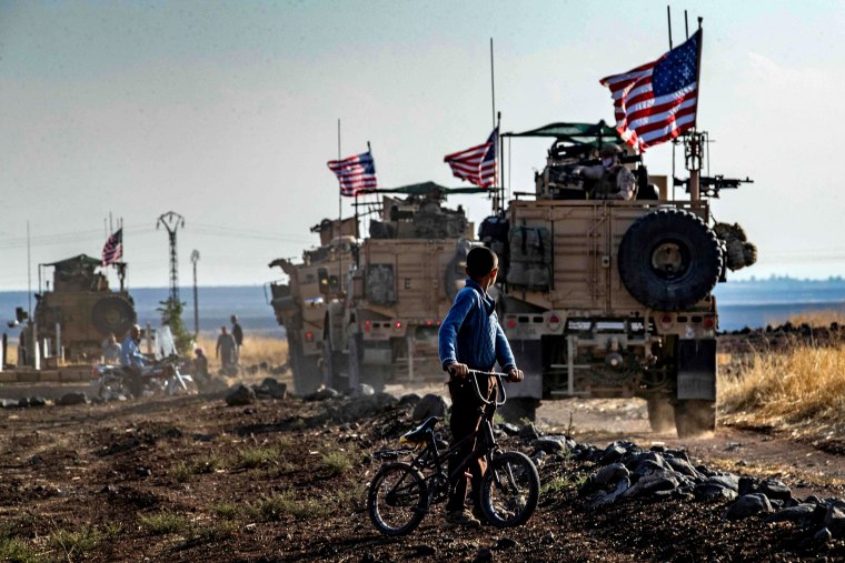 Image: A Syrian boy looks at a U.S. convoy patrolling near the Turkish border on Oct. 31, 2019.