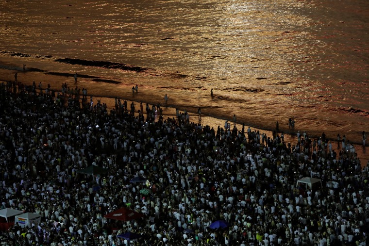 Image: People watch as fireworks explode over Copacabana beach during New Year celebrations in Rio de Janeiro