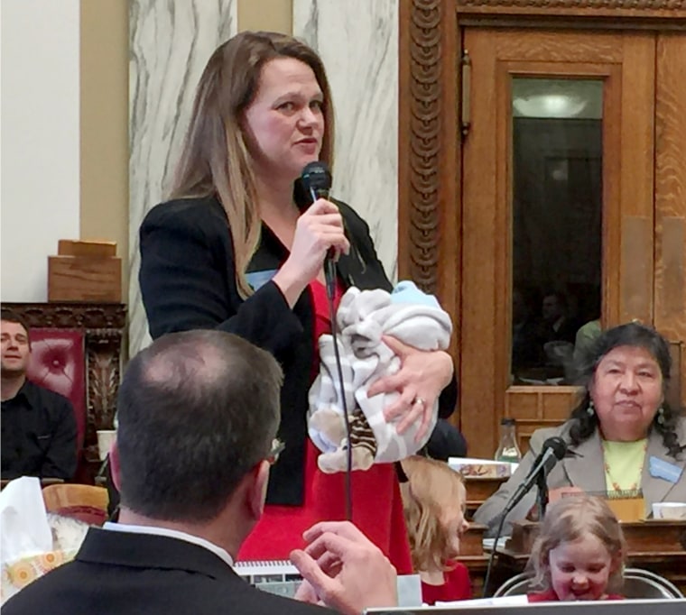 Image: Rep. Kimberly Dudik speaks on the house floor of the Montana legislature while holding her newborn on in March 2017.