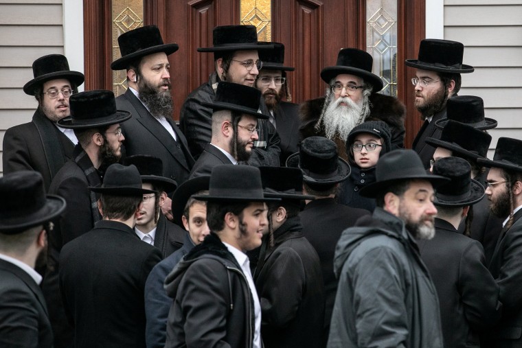 Image: Rabbi Chaim Rottenberg stands with people in front of his residence in Monsey