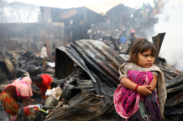 Image: Child looks on, whose shelter has been burned after a fire broke out in a slum in Dhaka