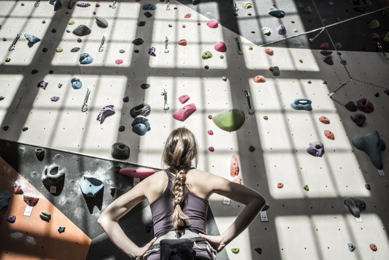 Image: Athlete examining rock wall in gym