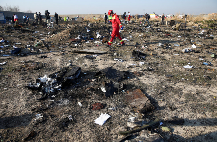 Image: A member of a rescue team walks among debris from a plane belonging to Ukraine International Airlines, that crashed after a take-off from Iran's Imam Khomeini airport, on the outskirts of Tehran