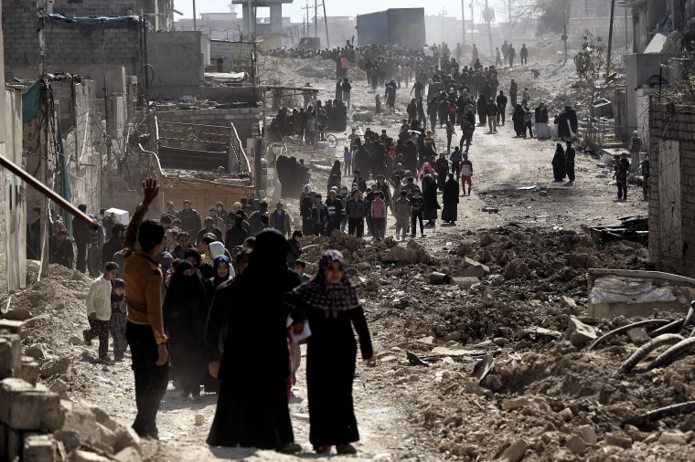 Image: People walk in west Mosul after a food distribution from the Iraqi troops on March 10, 2017 as Iraqi forces advance in the city during the ongoing battle to seize it from the jihadists of the Islamic State (IS) group