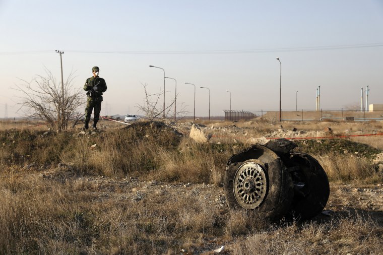 A police officer stands guard next to debris from an Ukrainian plane that crashed in Shahedshahr, southwest of the capital Tehran, Iran, on Jan. 8, 2020. A Ukrainian airplane carrying 176 people crashed on Wednesday shortly after takeoff from Tehran's main airport, killing all onboard.