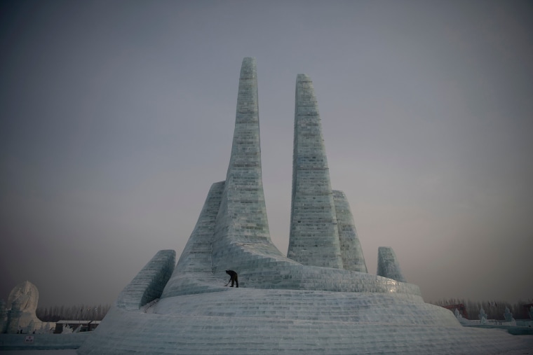 A worker clears some snow before tourists arrive at the Harbin International Ice and Snow Festival in Harbin, in China's northeast Heilongjiang province on Jan. 6, 2020. China's annual ice festival in Harbin kicked off late on Jan. 5 with couples lining up for a snow-themed mass wedding, swimmers braving frigid waters and frozen palaces rising from the ground.