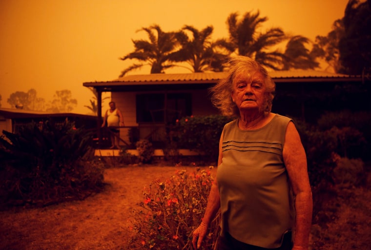 Nancy Allen stands outside a house as high winds push smoke and ash from the Currowan Fire towards Nowra, New South Wales, Australia on Jan. 4, 2020.