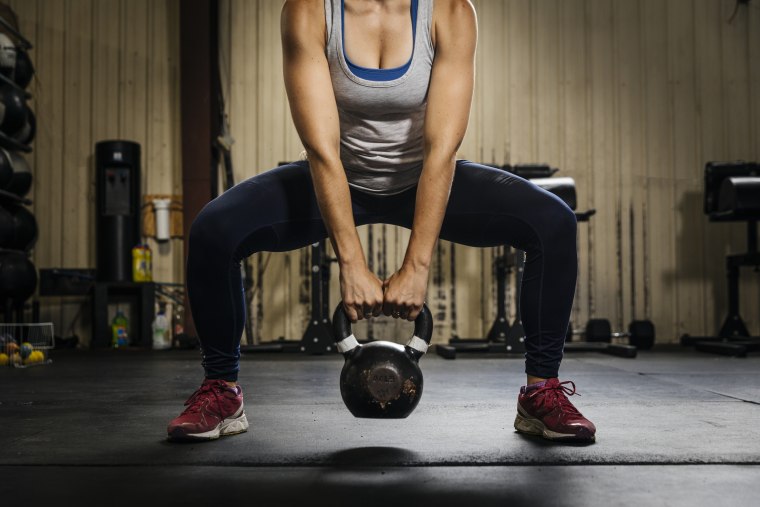 Female athlete exercising with kettlebell in gym