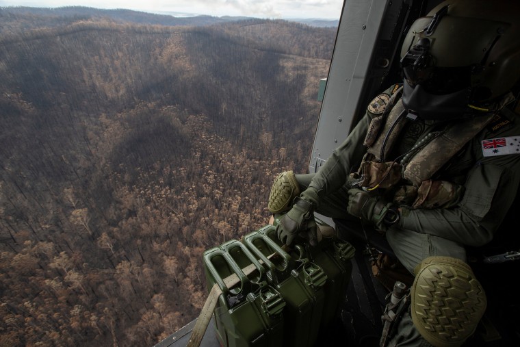 Image: A Royal Australian Navy aircrewman flies over the burnt countryside of New South Wales