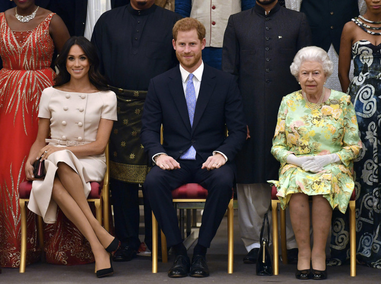 Image: Britain's Queen Elizabeth, Prince Harry and Meghan, Duchess of Sussex pose for a group photo at the Queen's Young Leaders Awards Ceremony at Buckingham Palace in London