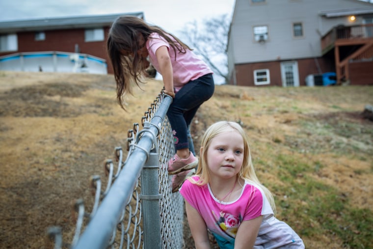 Kristen Snuffer, 9, looks as her four-year-old sister Brynn climbs over the backyard fence. Both girls, who were adopted out of foster care, were born dependent on opioids and removed from their biological homes because of parental substance abuse.