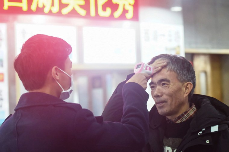 Image: A staff member checks the body temperature of a passenger after a train from Wuhan arrived at Hangzhou Railway Station in Hangzhou, China's eastern Zhejiang province