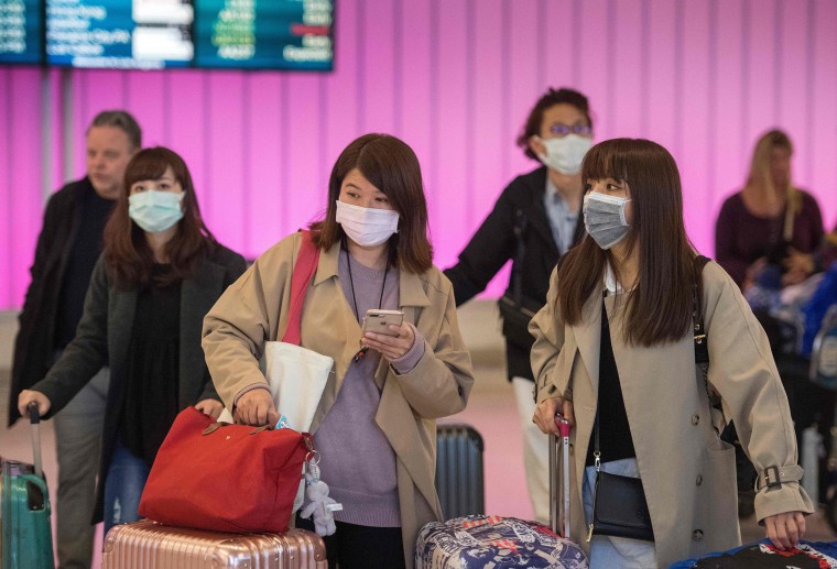 Passengers wear protective masks to protect against the spread of the coronavirus as they arrive at Los Angeles International Airport on Jan. 22, 2020.