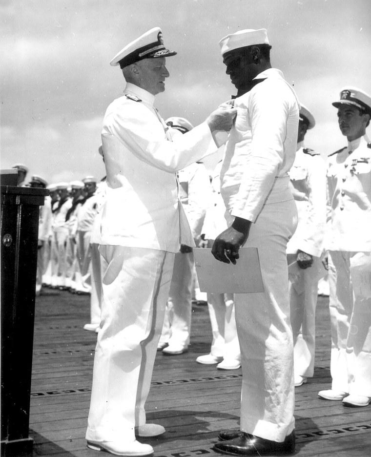 Admiral Chester W. Nimitz, USN, Commander-in-Chief, Pacific Fleet, pins the Navy Cross on Doris Miller, Steward's Mate 1/c, USN, at a ceremony on board a U.S. Navy warship in Pearl Harbor, T.H., May 27, 1942.