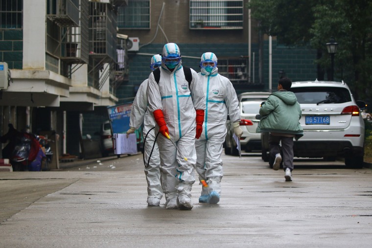 Image: Workers wearing protective clothing disinfect a residential area in Ruichang, in China's central Jiangxi province.