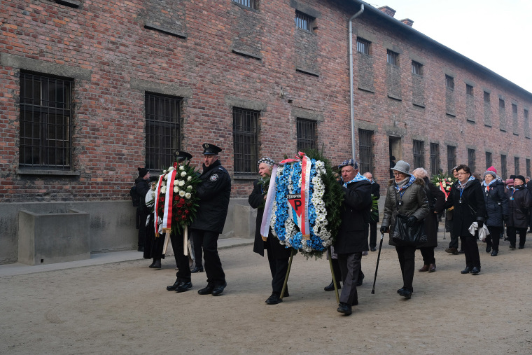 Image: A delegation of survivors of the Auschwitz and their families arrive to lay wreaths at the camp's execution wall on Monday.
