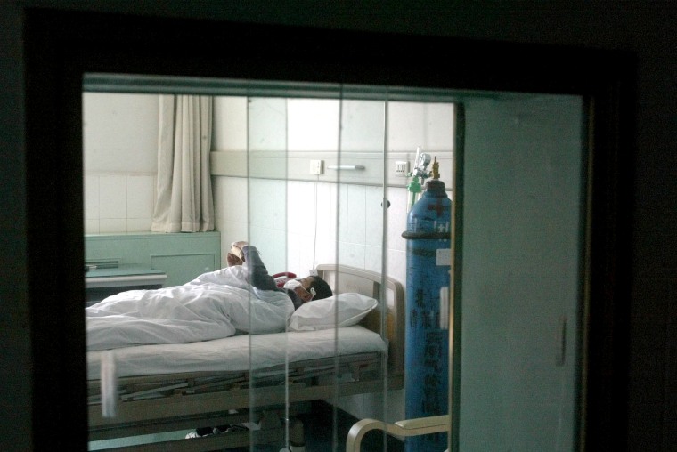 Image: A SARS patient receives treatment behind double-layer glass windows at a hospital in Beijing on April 13, 2003.