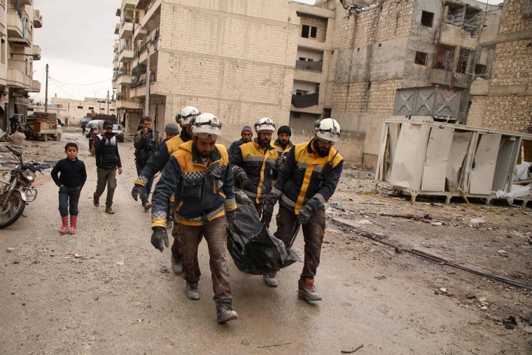 Image: White Helmets volunteers carry the body of a woman recovered from the rubble after an airstrike in the town of Ariha in Idlib Thursday.
