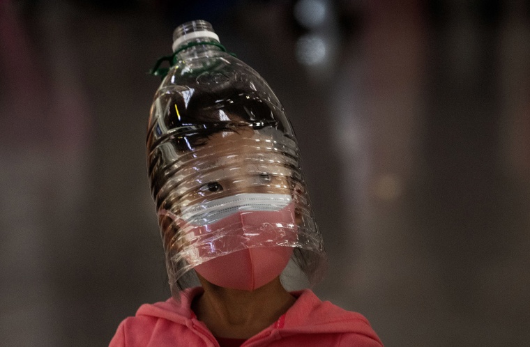 Image: A Chinese girl wears a plastic bottle as makeshift homemade protection and a protective mask while waiting to check in to a flight at Beijing Capital Airport