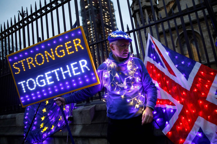 Image: Anti-Brexit protester holds illuminated Union and E.U. flags near the Houses of Parliament in London