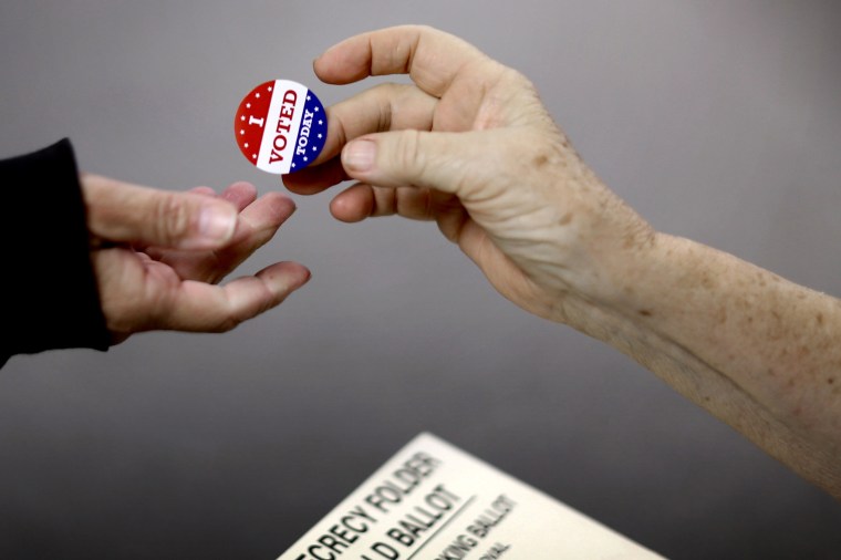Image: A voter receives an \"I Voted\" sticker after casting their ballot in Red Oak, Iowa, in 2014.