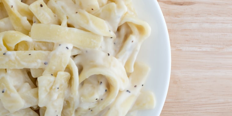 Plate of fettuccine alfredo on wood table top close view