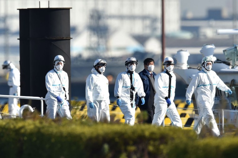 Image: Personnel clad in protective gear, tasked to provide care for suspected patients on board the Diamond Princess cruise ship, are seen at the Japan Coast Guard base in Yokohama