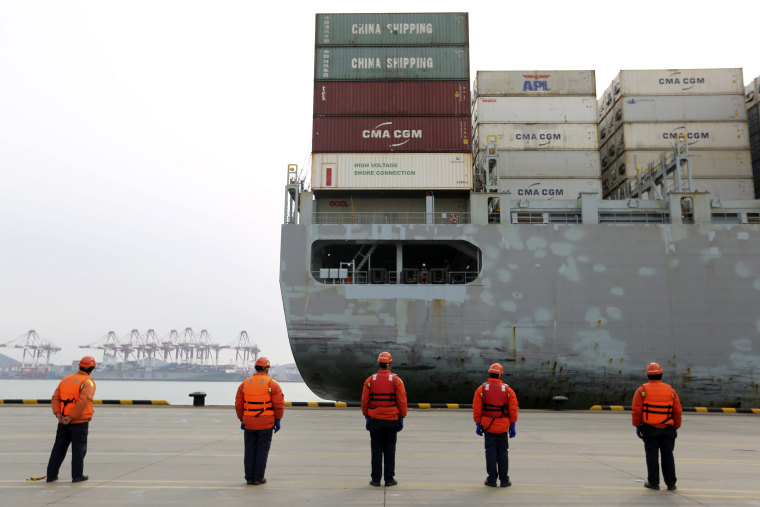 Image: Workers watch a container ship arrive at a port in Qingdao in east China's Shandong province on Tuesday.