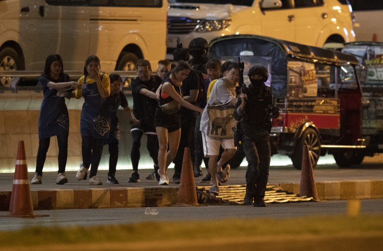 People who were able to get out of a mall are escorted outside by armed commando soldiers in Nakhon Ratchasima, Thailand, on Sunday. 