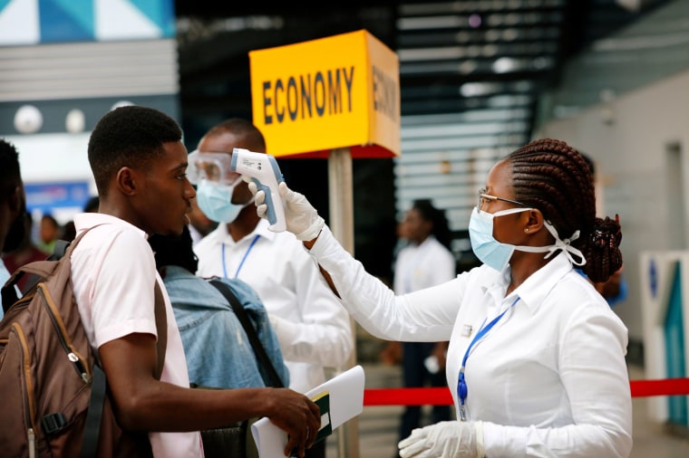 Image: A health worker checks the temperature of a traveler as part of a coronavirus screening procedure at the Kotoka International Airport in Accra, Ghana, on Jan. 30, 2020.