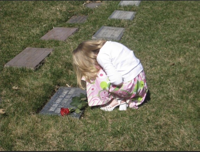 Dean's sister, Molly, who was born two years after Rylie's death, praying at her sister's grave.