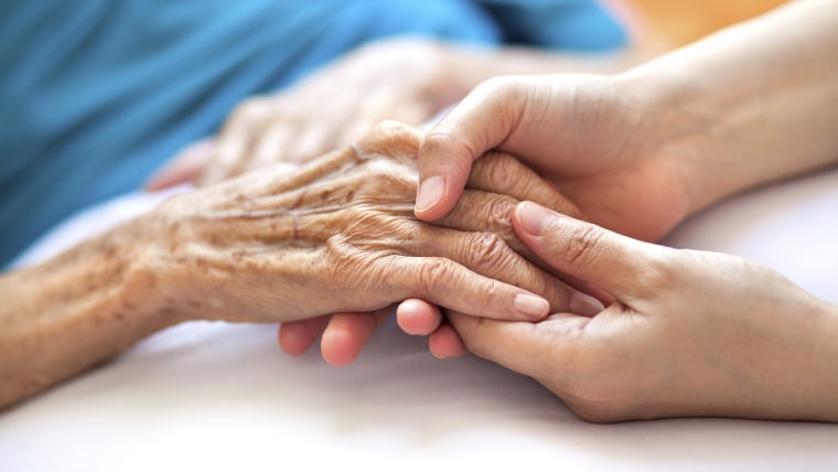 Image: Woman holding senior woman's hand on bed