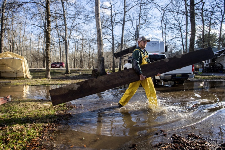 Image: Bradley Foster carries a wooden plank to help a neighbor move their camper after flooding in Decatur, Ala., on Feb. 8. 2020.