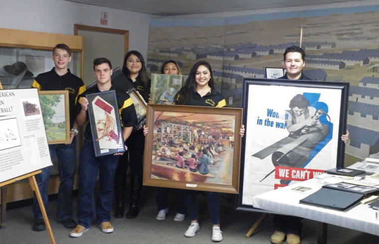 Students of Granada High School teacher John Hopper hold pieces of art in the old Amache museum, which is moving into a much larger building across the street.