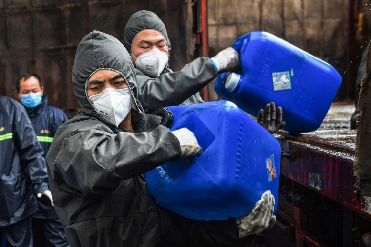 Image: Chinese police officers wearing protectieve gears transfer pails of disinfectant in Yunmeng county, outside Xiaogan City in China's central Hubei province