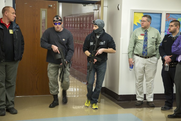 Image: Police officers acting as school shooters move through a group of school faculty and officials during an active shooter drill at Troy Buchanan High School
