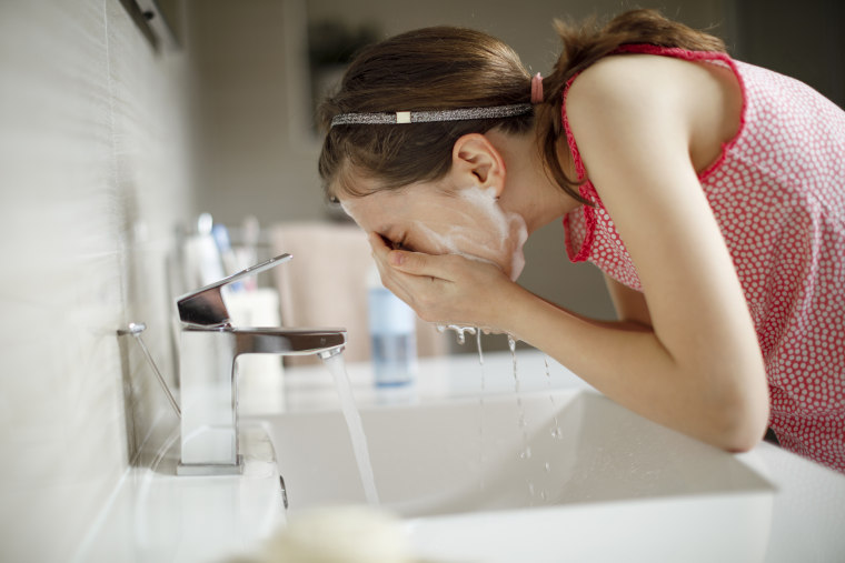 Image: Teenage girl washing her face with water