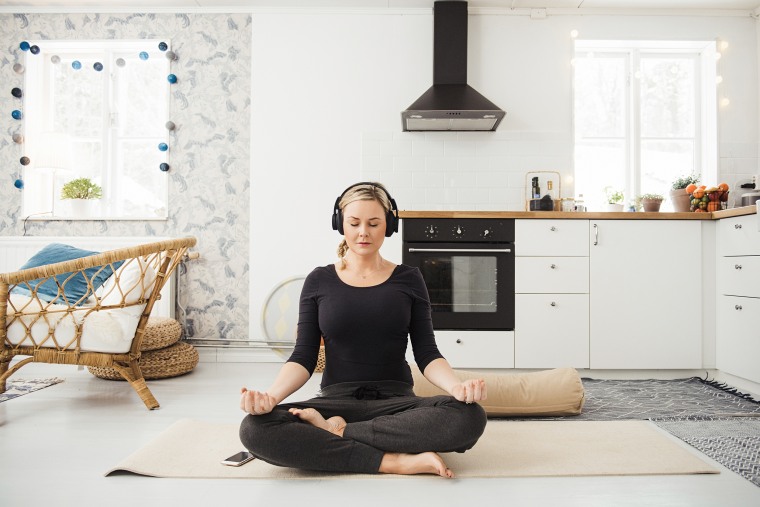 Real woman at home in kitchen doing yoga and meditation