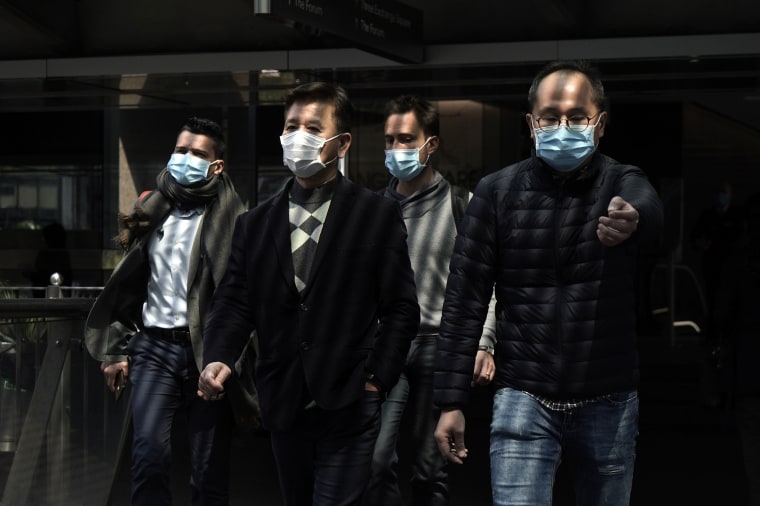 Image: People wearing masks walk in Central, a business district in Hong Kong