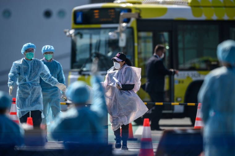 Image: A mask-clad passenger heads for a temperature check after disembarking from the Diamond Princess cruise ship, in quarantine due to fears of new COVID-19 coronavirus, at Daikoku pier cruise terminal in Yokohama