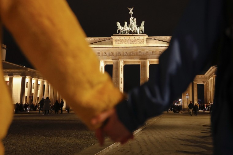 Image: People hold hands as they form a human chain, during a vigil for victims of last night's shooting in the central German town Hanau, at the Brandenburg Gate in Berlin, Germany